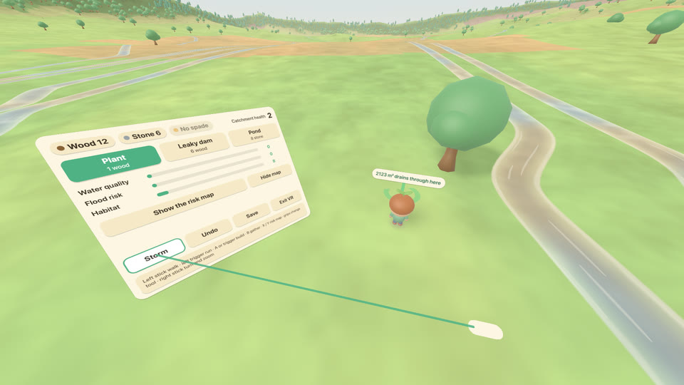 In a VR headset: the player's character stands on a tabletop landscape beside a stream and a tree, with a readout over its head. A panel at the left edge of the table shows wood, stone, the tools and catchment health, and a ray from the controller points at its Storm button.